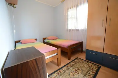 a room with two beds and a cabinet and a rug at President Holiday home in Utjeha