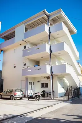 a white building with cars parked in front of it at Apartments Leyla in Ulcinj