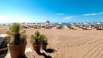a beach with chairs and umbrellas and the ocean at Beach Walk Apartments in Ulcinj