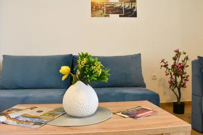 a vase with flowers on a table in front of a couch at Beach Walk Apartments in Ulcinj
