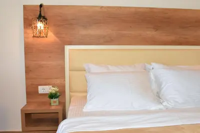 a bedroom with a white bed with a wooden headboard at Beach Walk Apartments in Ulcinj