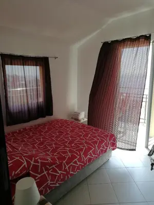 a bedroom with a red bed and a window at Apartman Marinkovic in Dobra Voda