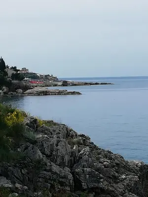 a large body of water with rocks in the foreground at Apartman Marinkovic in Dobra Voda