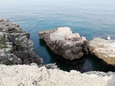 a person sitting on some rocks in the water at Apartman Marinkovic in Dobra Voda