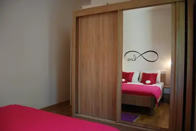 a bedroom with a mirrored closet with a red bed at Apartment Divina in Sveti Stefan