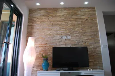 a living room with a tv and a brick wall at Apartment Divina in Sveti Stefan