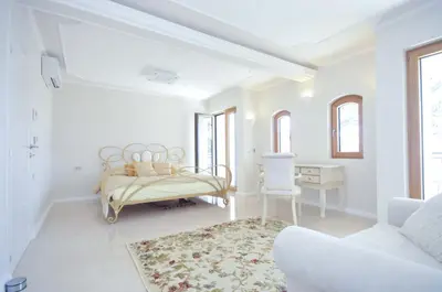 a white room with a bed and a chair at Villa St.George in Petrovac na Moru