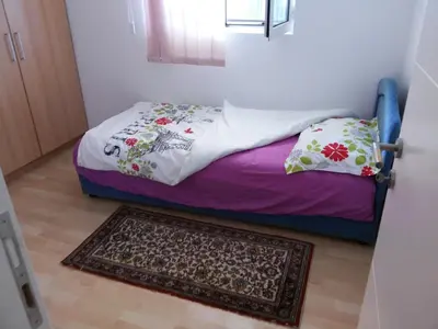 a small bed in a room with a rug at Apartman Any Bar in Bar