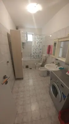 a bathroom with two toilets and a sink and a washing machine at Apartman Any Bar in Bar