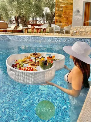 a woman in the water with a tray of food in a swimming pool at Eman Resort in Ulcinj