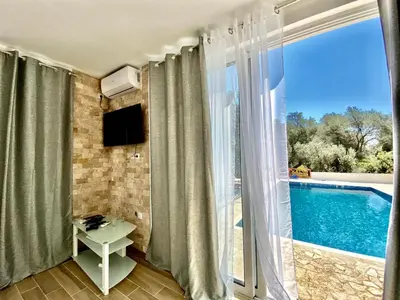 a room with a balcony with a pool and a television at Eman Resort in Ulcinj