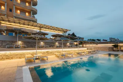 a swimming pool with chairs and umbrellas on a hotel at Hotel Blue Moon in Ulcinj