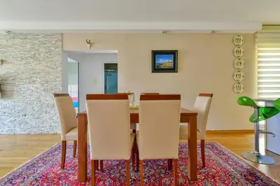 a dining room with a table and chairs on a rug at Lux Apartman Sofia in Sveti Stefan