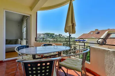 a balcony with a table and chairs and an umbrella at Lux Apartman Sofia in Sveti Stefan