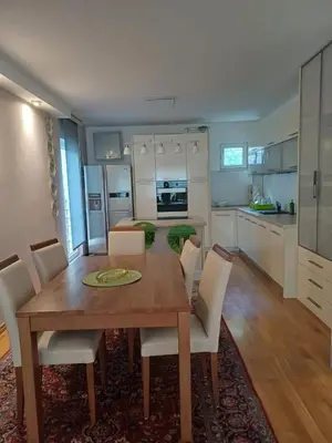 a kitchen and dining room with a wooden table and chairs at Lux Apartman Sofia in Sveti Stefan