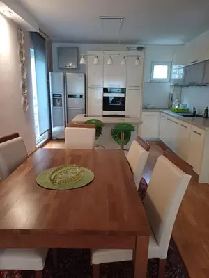 a kitchen and dining room with a wooden table and chairs at Lux Apartman Sofia in Sveti Stefan