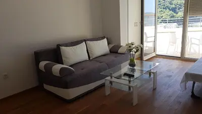 a living room with a couch and a glass table at Lux Apartment Vidovic in Rafailovici