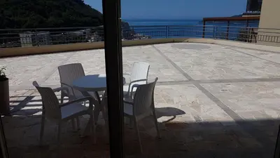 a patio with chairs and a table and a view of the ocean at Lux Apartment Vidovic in Rafailovici