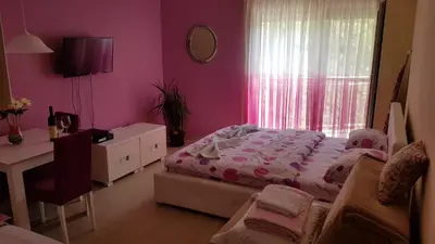a bedroom with a bed and a desk and a window at Lux Apartment Vidovic in Rafailovici