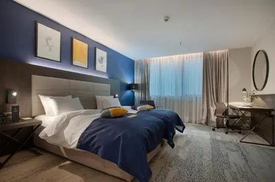 a bedroom with a large bed with a blue wall at voco - Podgorica by IHG in Podgorica