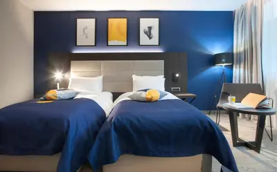 a bedroom with two beds and a blue wall at voco - Podgorica by IHG in Podgorica