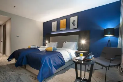 a hotel room with a large bed and a chair at voco - Podgorica by IHG in Podgorica