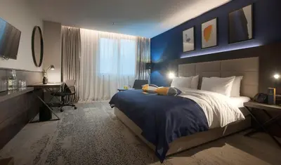 a bedroom with a large bed and a desk in it at voco - Podgorica by IHG in Podgorica