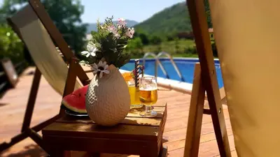 a table with a vase of flowers and a glass of beer at Apartments Djurovic in Virpazar