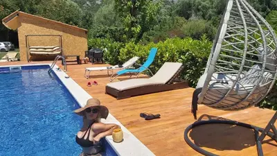 a woman in a hat sitting next to a swimming pool at Apartments Djurovic in Virpazar
