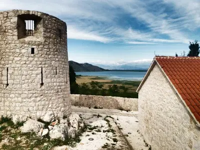 a castle with a view of the water and a building at Apartments Djurovic in Virpazar