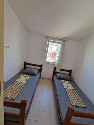 two beds in a small room with a window at Ago Apartmani in Dobra Voda