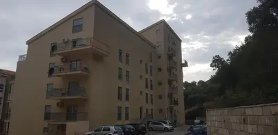 a tall building with cars parked in a parking lot at Urban Apartment in Petrovac na Moru