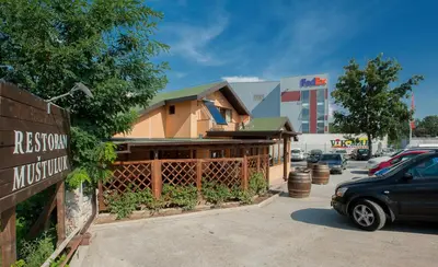 a building in a parking lot next to a car at Apartman in Danilovgrad