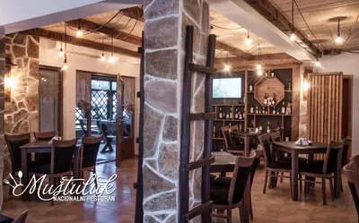 a restaurant with tables and chairs and a stone pillar at Apartman in Danilovgrad