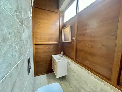a bathroom with a toilet and a wooden wall at Heart of the City Stunning city View,Balcony Free Wi-Fi in Podgorica