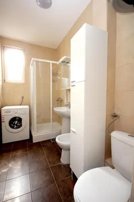 a white bathroom with a toilet and a sink at Apartments Drašković Mirišta in Petrovac na Moru