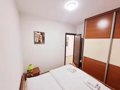 a bedroom with a bed and a wooden door at Centar New Loki Apartments in Budva