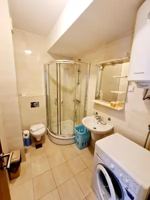 a bathroom with a shower and a sink and a washing machine at Centar New Loki Apartments in Budva