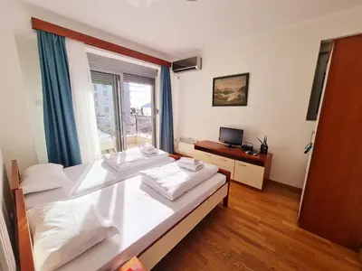a bedroom with a large white bed with a window at Centar New Loki Apartments in Budva