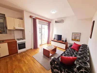 a living room with a couch and a kitchen at Centar New Loki Apartments in Budva