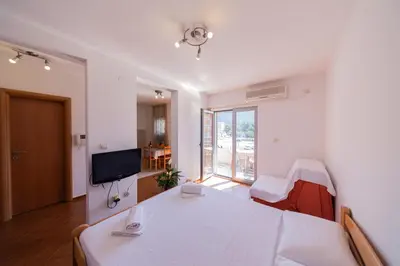 a room with a bed and a table and a television at SMS Apartments in Budva