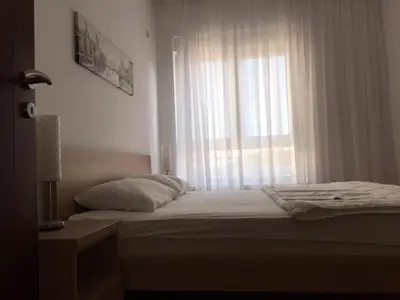 a bedroom with a bed and a window with curtains at City & Sea Apartments in Budva