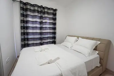 a bed with white sheets and white pillows and a window at Budva Bay Breeze Apartments in Budva