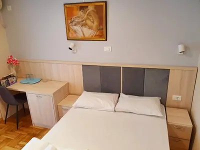 a bedroom with a bed and a desk and a painting at Apartments Pier in Budva