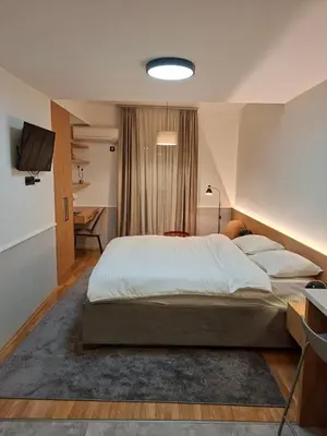 a bedroom with a large bed and a desk at Pg Apartment in Podgorica