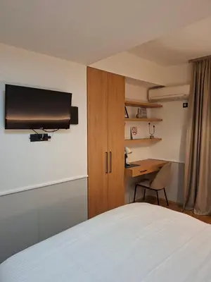 a bedroom with a bed and a desk and a television at Pg Apartment in Podgorica