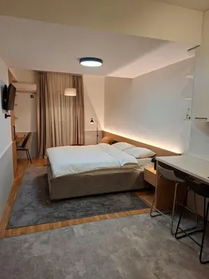 a bedroom with a large bed and a desk at Pg Apartment in Podgorica