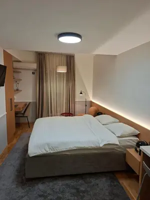 a bedroom with a large bed and a desk at Pg Apartment in Podgorica