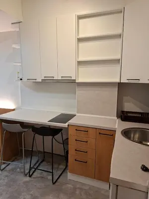 a kitchen with white cabinets and a table and a sink at Pg Apartment in Podgorica