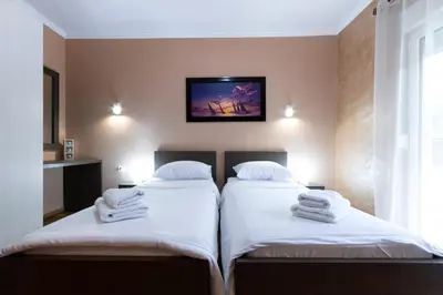 two beds in a room with a tv on the wall at Pejovic Residence Budva in Budva